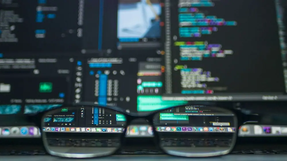 Source code on a monitor with glasses in the foreground
