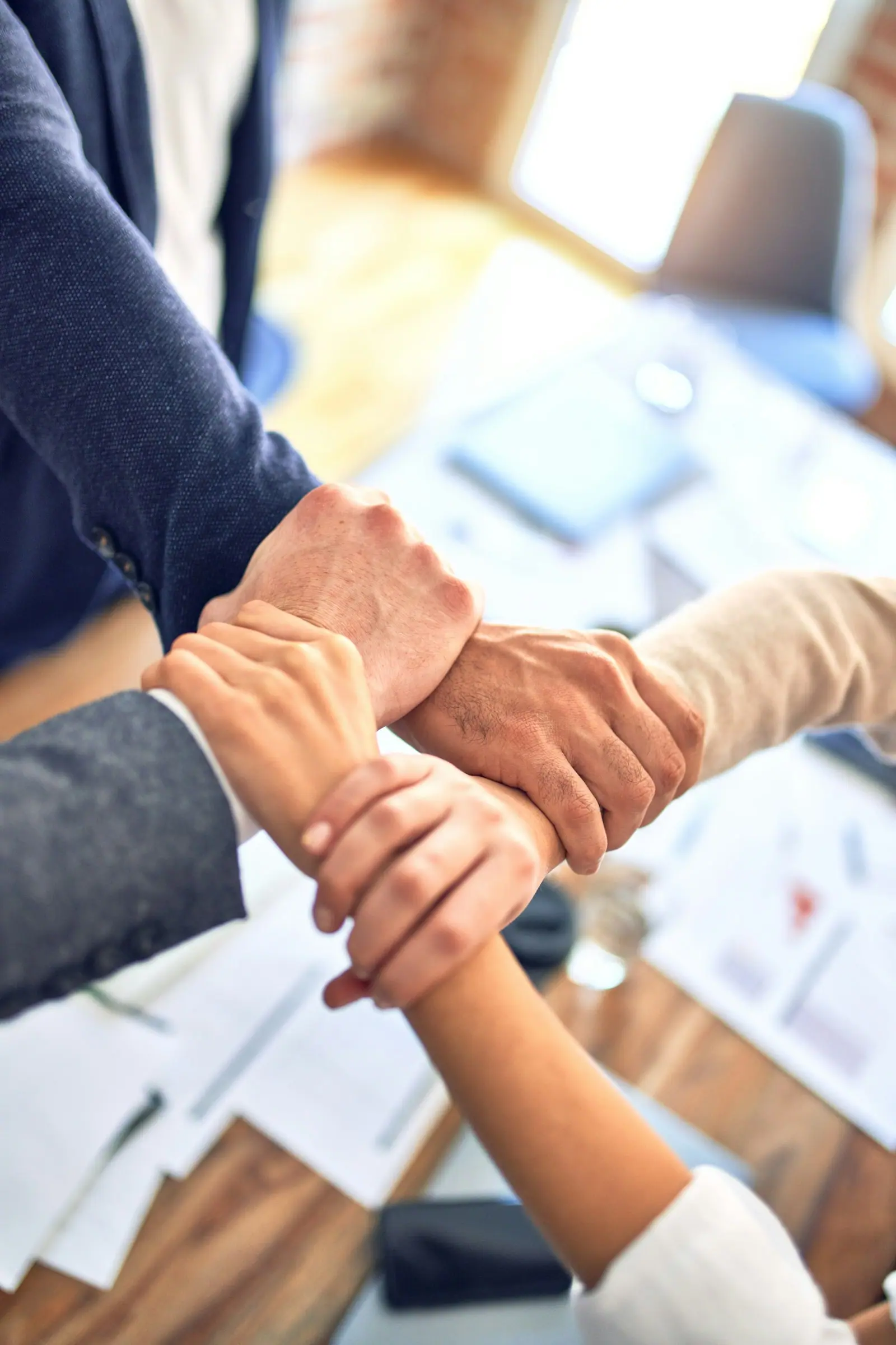 Partners joining hands across a table in a show of teamwork